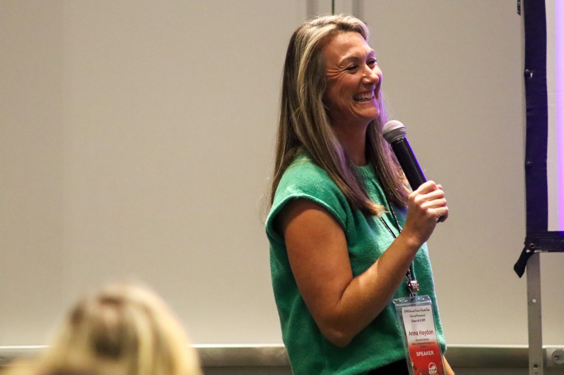 Woman in a Green Shirt Smiling During Presentation